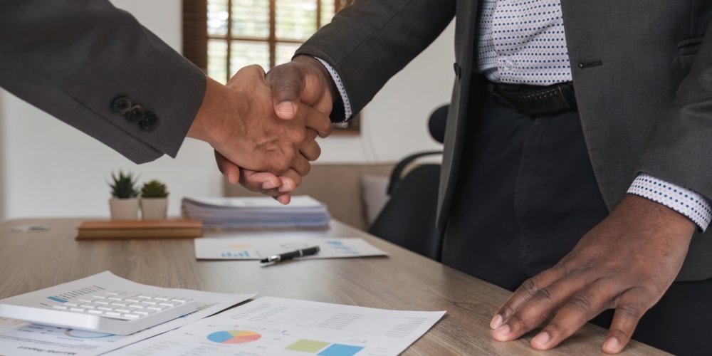 Close up of african business man and asian man shaking hands while at the office Close up of african business man and asian man shaking hands while at the office.