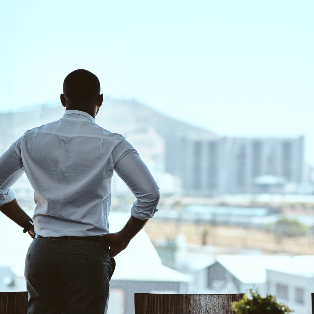 Rearview shot of a businessman looking out the window in an office. Rearview shot of a businessman looking out the window in an office.